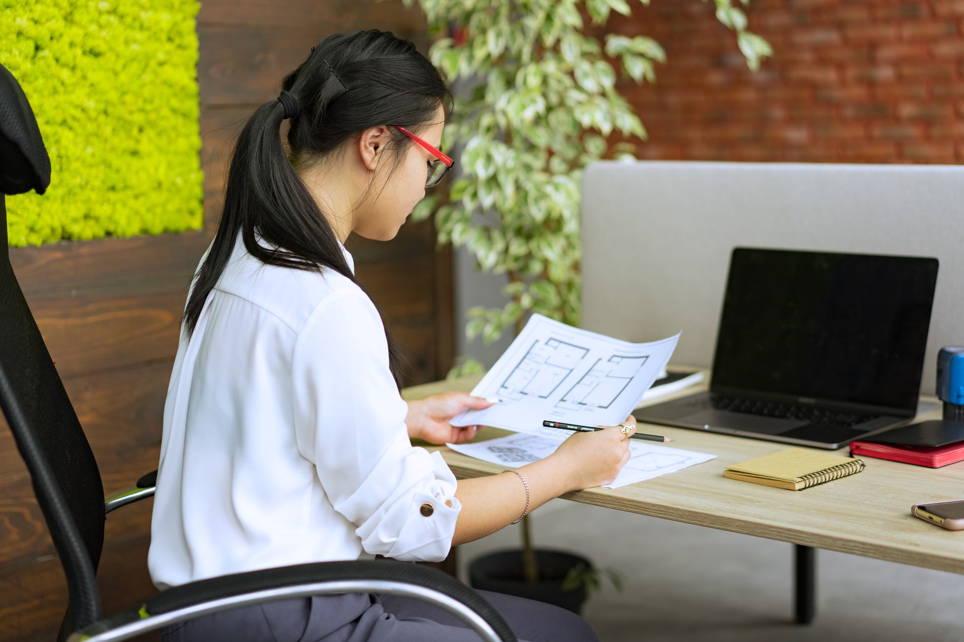 Homeowner using a laptop to prepare AI planning applications, with house extension drawings beside them