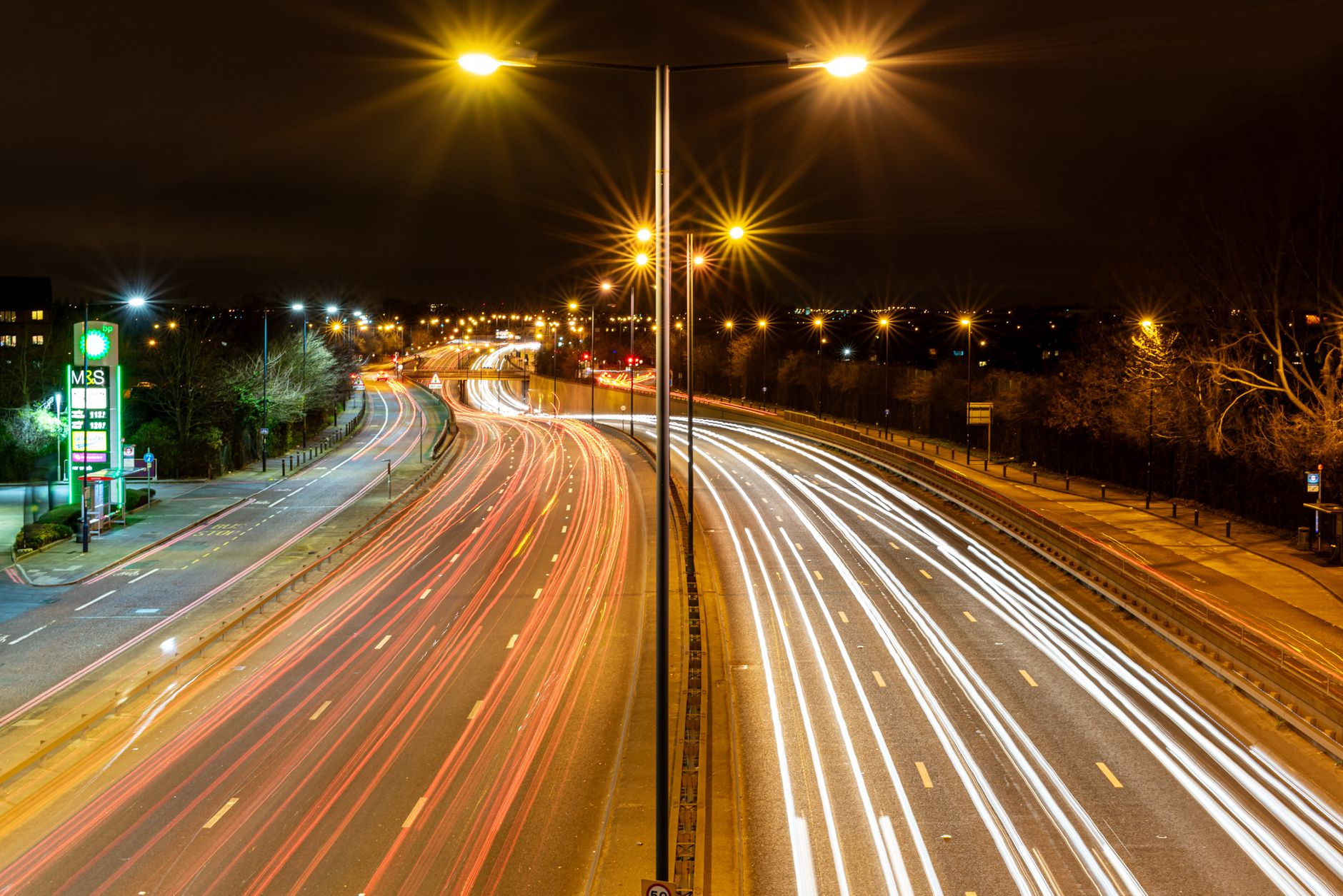 Overhead gantry with smart motorway cameras displaying variable speed limit signs, relevant to smart motorway camera fines UK