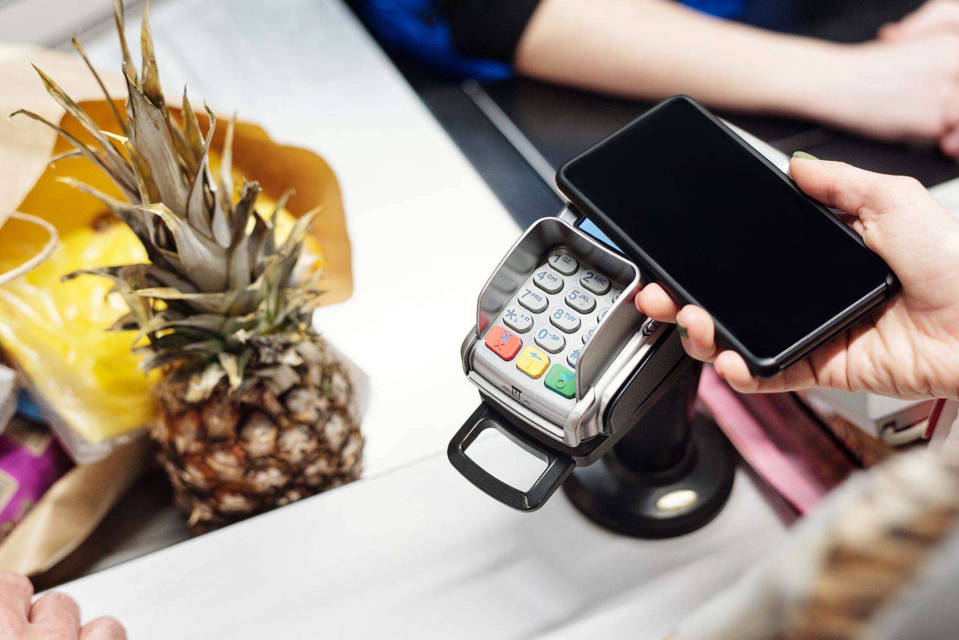 Person making a contactless payment at a market stall, illustrating cashless living UK problems